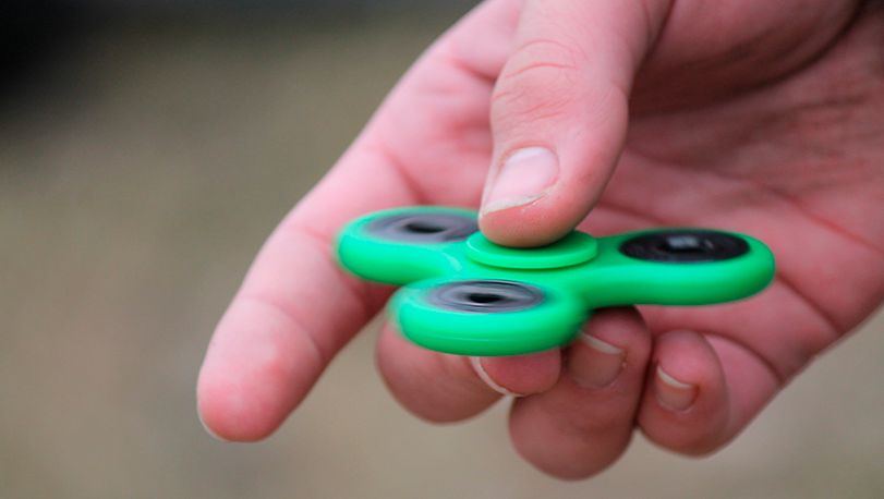 Mano de niño con un juguete verde llamado spinner