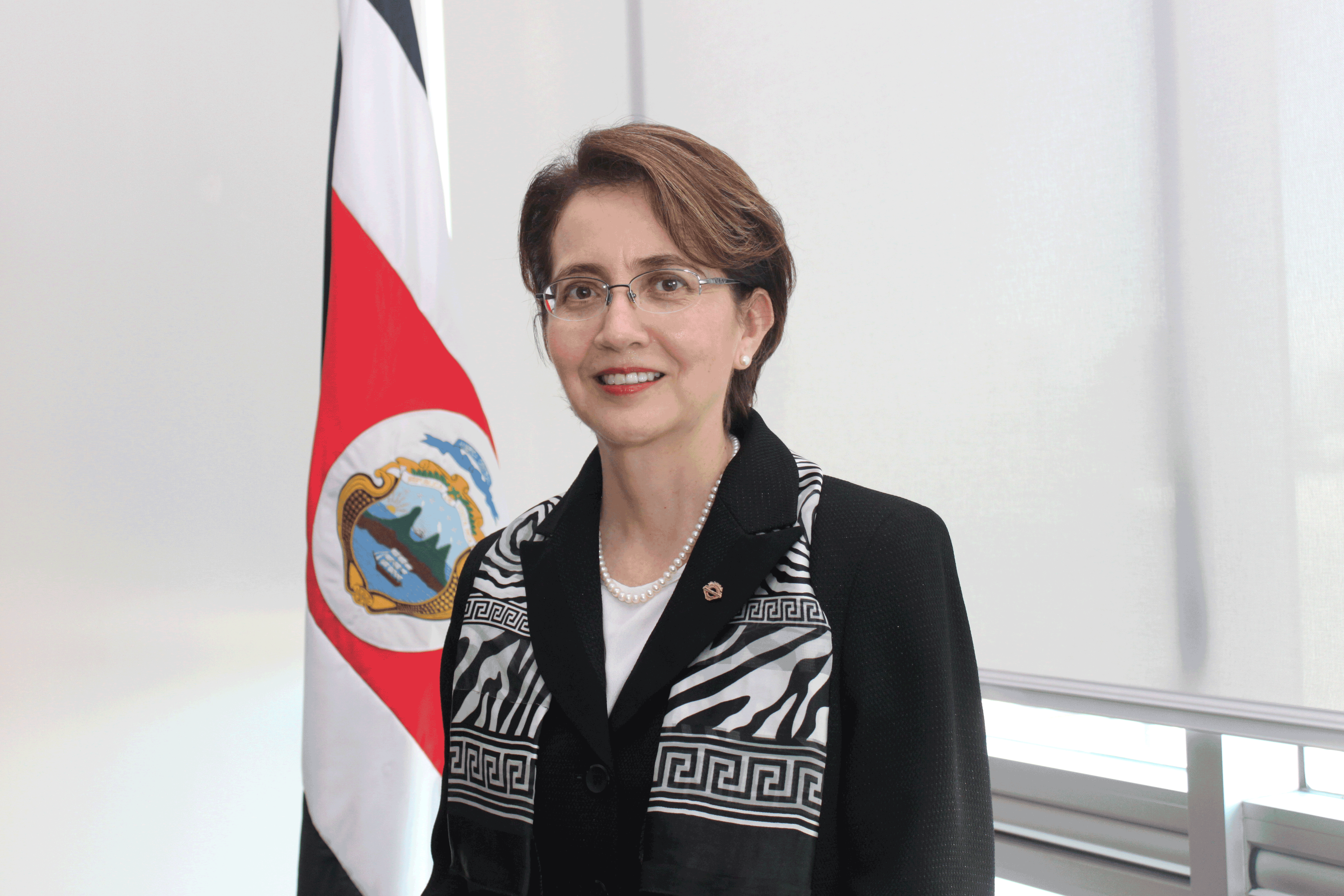 Magistrada Anamari Garro Vargas posa para la fotografía, detrás se muestra la bandera de Costa Rica